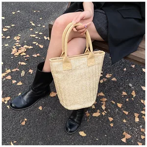 Detail of a large straw bucket bag showing herringbone weaving and reinforced fabric handles