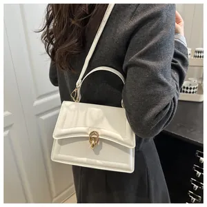 Detail der weißen Handtasche aus Leder mit goldenem Ringschloss und Ziernähten