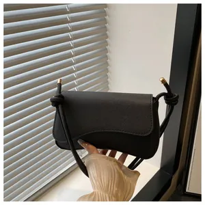 Detail van zwarte crossbodytas met kruistextuur en decoratieve knopen aan de riem