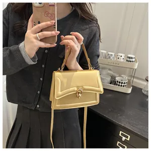 Detail einer ingwergelben PU-Lederhandtasche mit Metalldrehverschluss und Griff