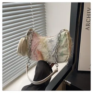 Dettaglio borsa in denim con motivo a stelle, catena d'argento e mini astuccio tondo