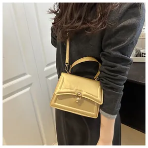 Schicke goldene rechteckige Handtasche mit Metallschnalle getragen von einem Model