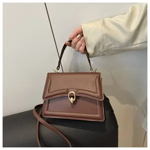Detail einer braunen Lederhandtasche mit schicker goldener Metallschnalle und Griff
