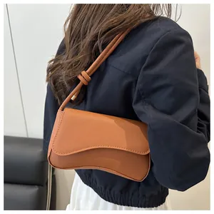 Detailopname van bruine baguette-tas van saffianoleer met fijne textuur en stiksels