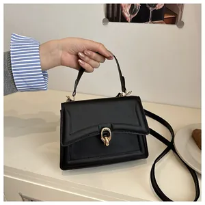 Details einer schicken schwarzen Handtasche mit goldener Ringschnalle und Schultergurt