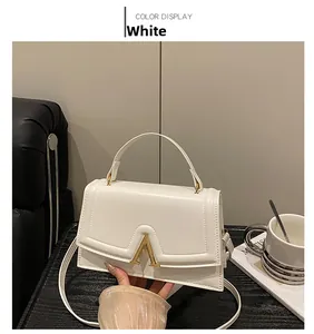 Detailansicht einer weißen Lederhandtasche mit modischem goldener A-förmigem Metallverschluss