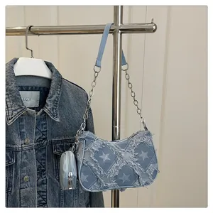 Dettaglio borsa denim con motivo stella bianca, tracolla a catena e piccolo borsellino