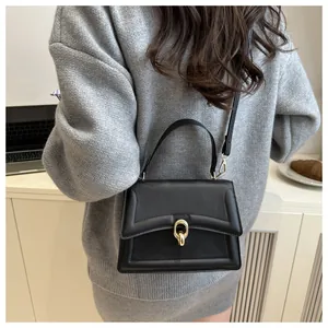 Details einer schwarzen Lederhandtasche mit goldenem Verschluss im Lifestyle-Look