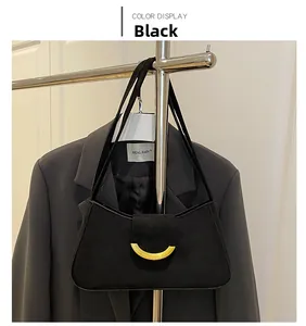 Dettaglio borsa a spalla in camoscio nero con fibbia dorata a mezzaluna e doppia tracolla