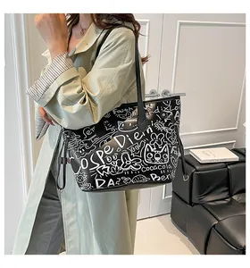 Dettaglio di una borsa tote in pelle nera con stampe graffiti indossata con un trench verde