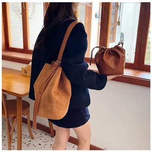 Detail view of large brown vintage suede bucket bag and small leather drawstring pouch