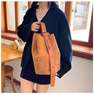 Detail of vintage brown suede bucket bag with smooth leather strap and metal buckle