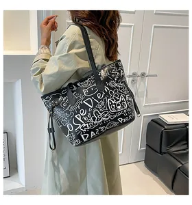 Dettaglio della borsa tote nera con graffiti bianchi e illustrazioni di gattini
