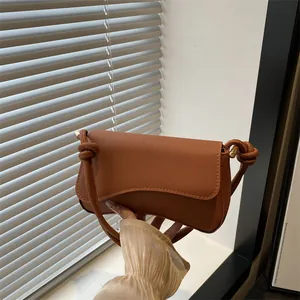 Elegante karamelbruine baguette tas met kruislingse textuur en knoopdetail op riem