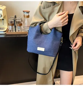 Blue denim canvas bucket bag with leather trim and shoulder strap for casual styling
