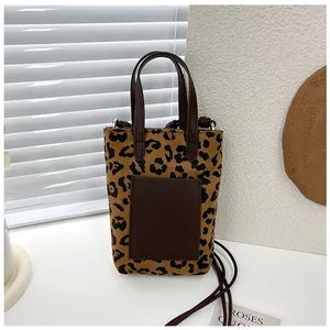 Detailed view of leopard print tote bag with brown leather pocket and slim strap