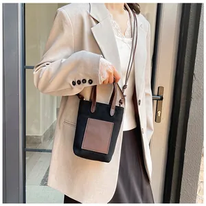Close-up of a stylish canvas and leather crossbody bag worn with a beige blazer