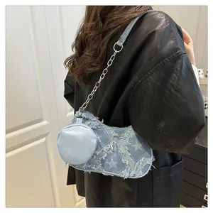 Dettaglio borsa in denim blu con stelle, frange consumate e tracolla a catena
