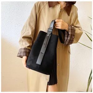 Close-up of black suede bucket bag showing its matte texture and leather handle details