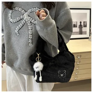 Détail du sac à main en peluche noire avec broderie ours et breloque en peluche blanche