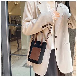 Minimalist black small crossbody bag with brown patch and slim shoulder strap on model