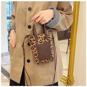 Detailed close-up of leopard print canvas mini bag with brown leather handles and strap
