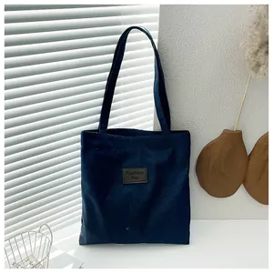 Macro detail of dark blue denim tote bag featuring a brown leather Fashion Bag patch