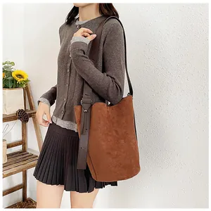 Detail of the brown suede bucket bag featuring a wide shoulder strap and matte texture