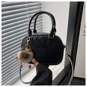 Détail du sac en similicuir noir avec texte LHCO et charmant ours en peluche marron