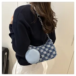 Dettaglio della borsa sottobraccio in denim a scacchi con bordi sfrangiati e mini charm