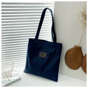 Detail of dark blue canvas tote bag featuring a leather Fashion Bag label on the front
