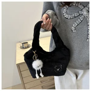 Détail du sac à main noir en peluche avec patch ours et pendentif monstre blanc