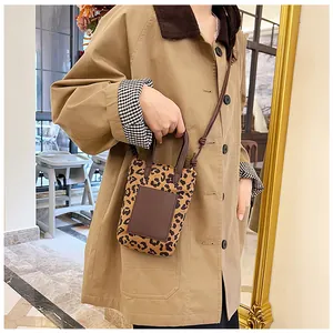 Mini leopard print crossbody bag styled with a khaki trench coat in a cozy cafe setting