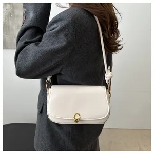 Detail of white French baguette bag with gold metal clasp and minimalist knot strap