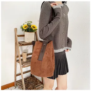 Detail view of large brown suede bucket bag with leather strap and vintage matte texture
