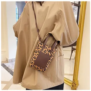 Detail shot of a trendy leopard print crossbody phone bag worn over a khaki coat