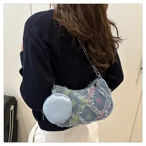 Dettaglio della borsa sottobraccio in denim azzurro con motivo a stelle e catena