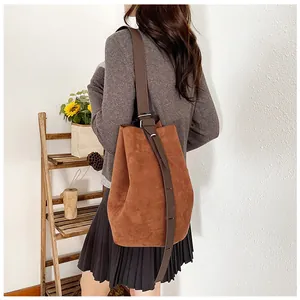 Detailed shot of brown matte suede bucket bag with adjustable dark leather shoulder strap