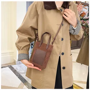 Brown suede crossbody phone bag styled with a khaki trench coat for a retro look