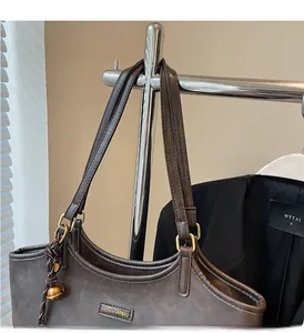 Detail of dark brown tote bag with fashion logo, gold rings and sturdy handles