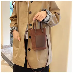 Detailed shot of brown suede mini tote bag with dark brown leather pocket and crossbody strap