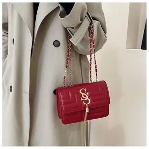 Detail of red quilted leather bag with gold S-logo, fringe tassel, and chain strap