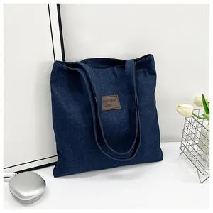 Close-up of a blue denim tote bag with brown leather patch and white tulip decor