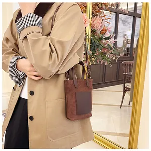 Lifestyle shot of a brown suede mini tote bag with a dark brown square leather pocket