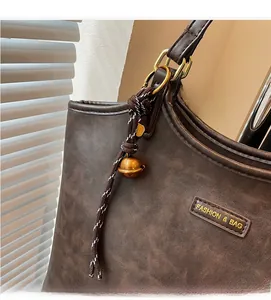 Close-up of brown tote bag with vintage texture, golden D-ring and woven rope charm