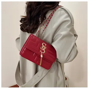Detail of red quilted square bag with gold interlocking logo and metallic tassel