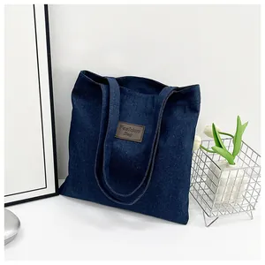 Detail of blue denim tote bag with brown leather patch and embossed Fashion Bag text
