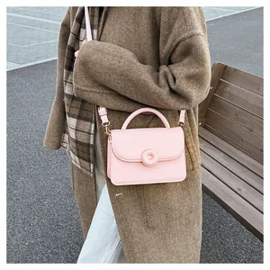 Outdoor look of a pink crossbody square bag with gold hardware on a wool coat