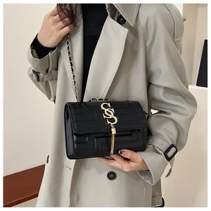 Macro detail of geometric textured black leather bag with gold tassel and chain strap