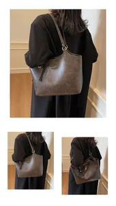 Close-up of a large brown leather tote bag with vintage oil wax texture and silver brand plaque